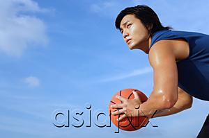 AsiaPix - Man holding basketball, looking away, side view