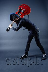 AsiaPix - Man with mohawk, holding guitar, over shoulder, bending down
