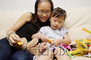AsiaPix - Mother and daughter on sofa, playing with toys
