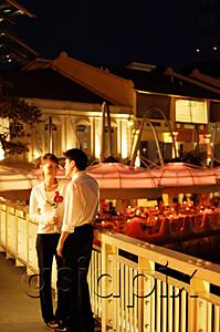 AsiaPix - Couple standing on bridge, woman holding roses
