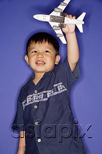 AsiaPix - Young boy playing with toy airplane