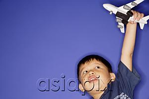 AsiaPix - Young boy playing with toy airplane