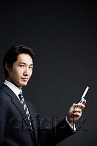 AsiaPix - Businessman looking at camera, holding mobile phone