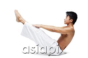 AsiaPix - Man doing yoga, sitting on floor, raising leg