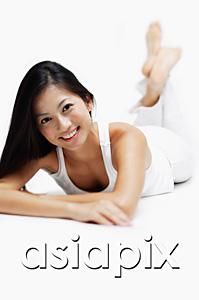 AsiaPix - Woman lying on front, legs crossed at the ankle, smiling at camera