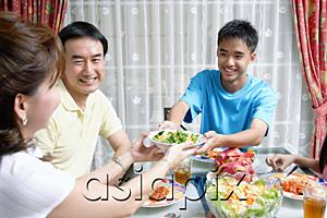 AsiaPix - Mother and son passing food to each other at dining table