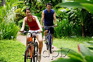 AsiaPix - Couple cycling through a park, smiling