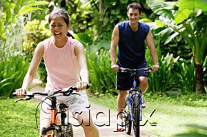 AsiaPix - Young couple cycling through a park