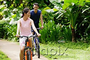 AsiaPix - Couple cycling together through a park