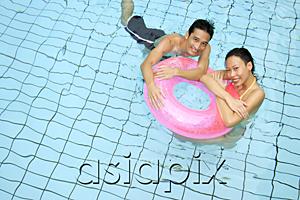 AsiaPix - Couple in swimming pool leaning on inflatable ring, looking at camera