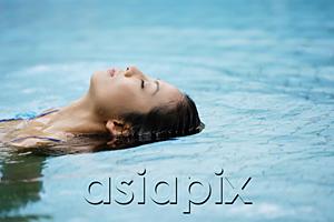 AsiaPix - Woman floating in swimming pool
