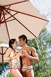 AsiaPix - Couple standing under umbrella, holding drinks, looking at each other
