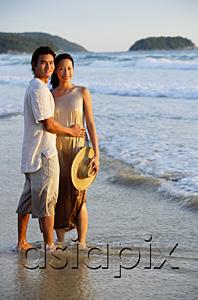 AsiaPix - Couple standing on beach, ankle deep in water, looking at camera