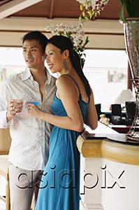 AsiaPix - Couple standing side by side, holding drinks, looking away