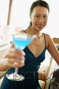 AsiaPix - Woman sitting at bar counter, holding cocktail, smiling