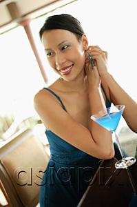 AsiaPix - Woman sitting at bar counter, looking away, smiling