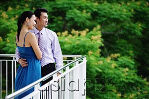 AsiaPix - Couple standing on balcony, looking away, side view