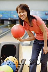 AsiaPix - Woman at bowling alley with bowling ball, smiling at camera