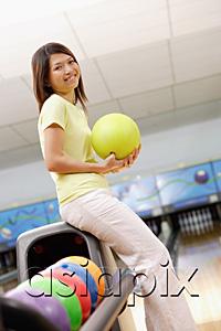 AsiaPix - Woman at bowling alley with bowling ball, smiling at camera
