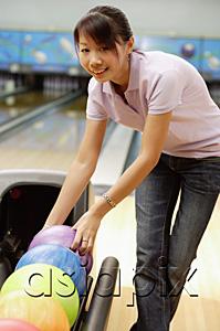 AsiaPix - Woman selecting ball at bowling alley