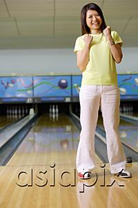 AsiaPix - Woman standing at bowling alley, hands in fists, smiling