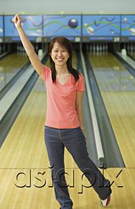AsiaPix - Woman standing at bowling alley, arm outstretched