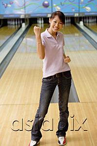 AsiaPix - Woman standing at bowling alley, smiling, making a fist