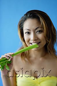 AsiaPix - Woman looking at camera, eating celery