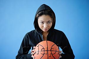 AsiaPix - Woman wearing hooded shirt, holding basketball, looking at camera