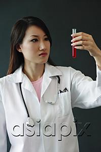 AsiaPix - Female doctor looking at test tube, serious expression