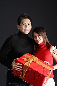 AsiaPix - Couple holding gift, looking at camera