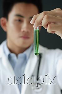 AsiaPix - Doctor looking at test tube filled with green liquid