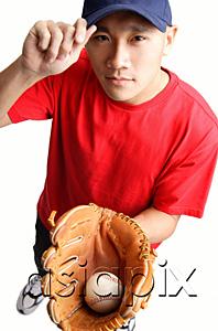 AsiaPix - Young man holding baseball glove and ball, adjusting cap