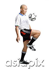 AsiaPix - Young man in soccer uniform, using knee to hit ball