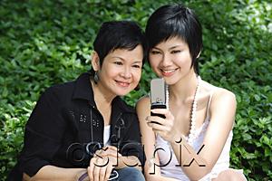 AsiaPix - Women side by side, smiling, looking at mobile phone