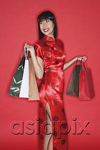 AsiaPix - Woman in red cheongsam, against red wall, carrying shopping bags