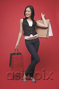 AsiaPix - Woman carrying shopping bags, standing against red wall