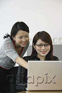 AsiaPix - Businesswoman using laptop, another woman looking her shoulder