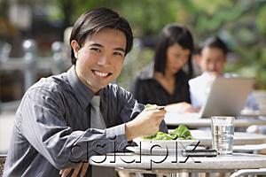 AsiaPix - Businessman having lunch at outdoor cafe, smiling at camera