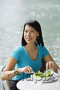 AsiaPix - Young woman in cafe, having salad, looking away