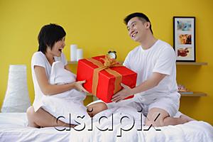 AsiaPix - Couple sitting on bed, man giving woman present
