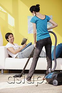 AsiaPix - Woman vacuuming, man sitting on sofa with book, smiling at her