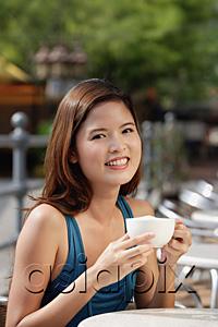 AsiaPix - Woman having coffee in cafe, smiling at camera