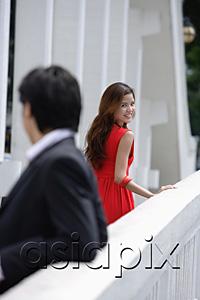 AsiaPix - Man leaning on bridge railing, woman in background turning to look at him
