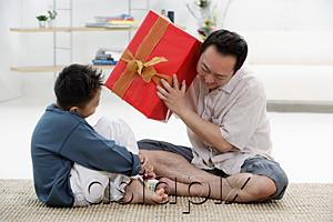 AsiaPix - Father and son at home, father holding big gift box