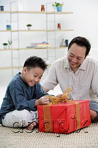 AsiaPix - Boy opening gift box, father next to him