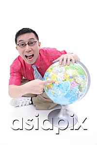 AsiaPix - Man sitting on floor, pointing to globe, looking at camera