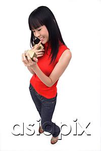 AsiaPix - Young woman holding gift box, finger on mouth