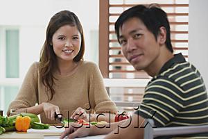 AsiaPix - Couple looking at camera, woman chopping vegetables