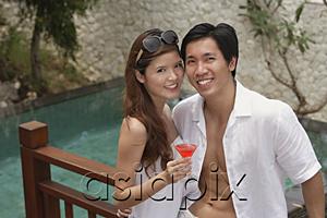 AsiaPix - Couple standing side by side, smiling at camera, swimming pool behind them